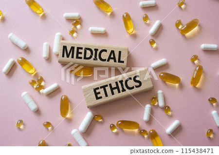 Medical Ethics symbol. Concept word Medical Ethics on wooden blocks. Beautiful pink background with pills. Medicine and Medical Ethics concept. Copy space 115438471