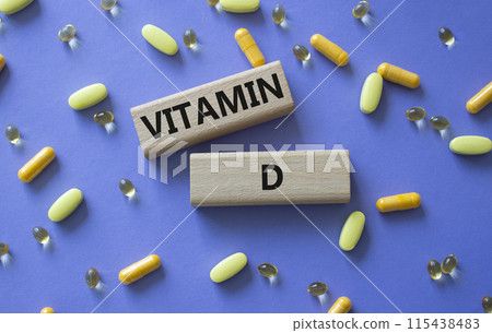 Vitamin D symbol. Concept word Vitamin D on wooden blocks. Beautiful purple background with pills. Medicine and Vitamin D concept. Copy space 115438483