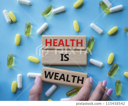 Health is Wealth symbol. Concept word Health is Wealth on wooden blocks. Doctor hand. Beautiful blue background with pills. Medicine and Health is Wealth concept. Copy space Health is Wealth symbol. Concept word Health is Wealth on wooden blocks. Doctor hand. Beautiful blue background with pills. Medicine and Health is Wealth concept. Copy space 115438542