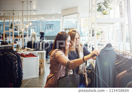 Smile, shopping and help customer with clothes for decision, sales or discount at luxury mall. Fashion, retail store or client with fabric at boutique for choice or advice with women talking at shop 115438684