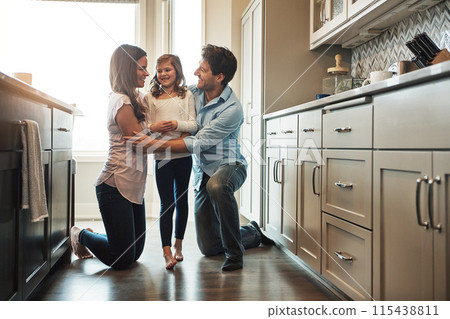 Parents, girl and hug in kitchen for love, conversation and support for relationship in home. Mother and father, daughter and together in embrace for security, speaking and bonding in family house 115438811