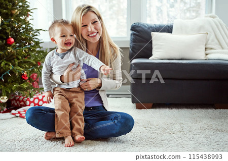 Mother, baby and happy christmas while on floor in living room, holiday and cuddle for love. Smile, motherhood and toddler with woman together, hug and play by sitting for relationship at home 115438993