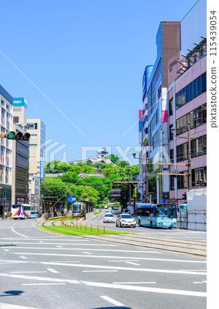 熊本城映襯著藍天和市中心地區運行的電車和道路交通（熊本市道町筋） 115439054