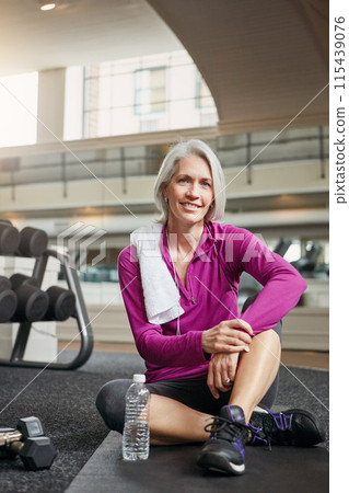 Gym, floor and portrait of mature happy woman with smile, relax and dumbbells with water bottle at workout. Exercise, training and confident female athlete on break for fitness, health and wellness 115439076