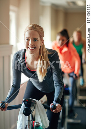 Woman, exercise bike and class at gym, training and cycling for fitness or spinning studio. Female person, cardio and stationary machine for workout challenge, aerobics instructor and equipment 115439311