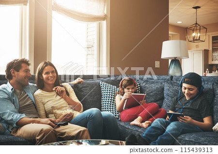 Family, children and parents with tablet on couch, watching tv and streaming with bonding in living room. Mother, father and kids with headphones, subscription or movies with smile in lounge at house 115439313