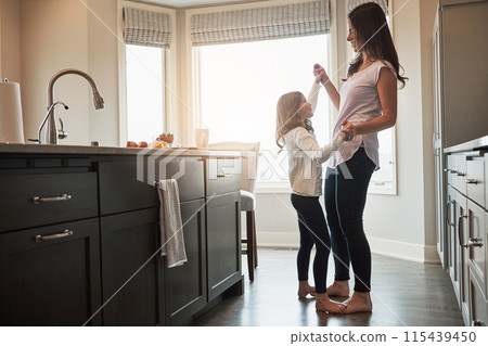 Mother, daughter and dancing in kitchen, happiness and love in house, care and feet of kid on mom. Home, fun and smile for bonding in apartment, teaching and morning for support and holding hands 115439450