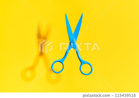 Bright blue scissors over yellow background Bright blue scissors over yellow background 115439518