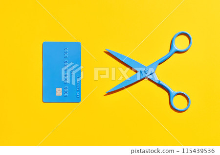 Blue scissors and credit card over yellow background 115439536