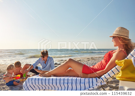 Chair, summer or kids with woman at beach on holiday vacation or weekend together with dad or family. Father, calm mother or children siblings at sea for bonding or break in nature in Spain to relax 115439632