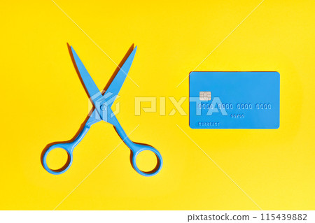 Blue scissors and credit card over yellow background 115439882