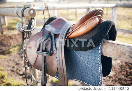 Saddle, countryside and farm on stable fence for riding or equestrian sports in nature or park. Background, agriculture or field in Texas ranch with seat or equipment for outdoor hobby in paddock Saddle, countryside and farm on stable fence for riding or equestrian sports in nature or park. Background, agriculture or field in Texas ranch with seat or equipment for outdoor hobby in paddock 115440240