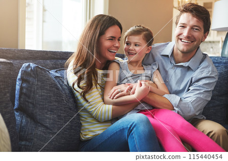 Hugging, portrait and child with parents on sofa in home relaxing with care, fun and love together. Happy, bonding and girl kid embracing with mother and father in living room at family house. 115440454