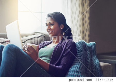 Home, Indian woman and tablet on couch to laugh, relax and comfortable with technology in living room. Apartment, happy girl or digital for streaming comedy, funny film or watch movie with coffee cup 115440846