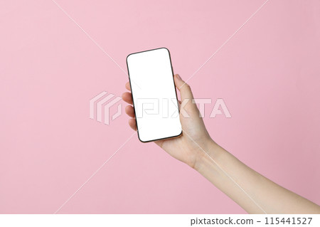 Female hand holding a smartphone on a pink background 115441527