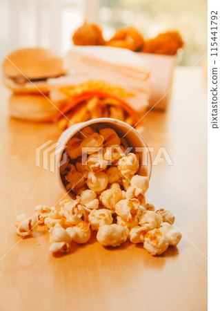 A bucket of popcorn, top-view, warm colors, light brown wooden background, flat lay, daylight macro close-up 115441792