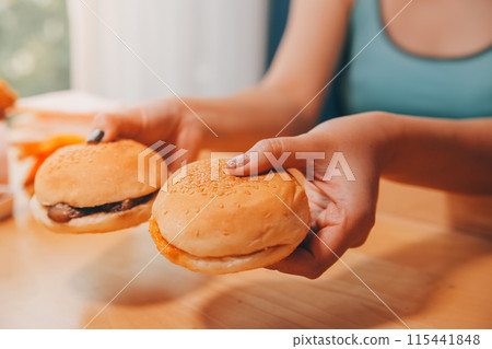 Binge eating disorder concept with woman eating fast food burger, fired chicken , donuts and desserts Binge eating disorder concept with woman eating fast food burger, fired chicken , donuts and desserts 115441848