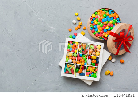Set of different sweet candy in a paper box with a satin ribbon on a colored background. Holiday concept 115441851