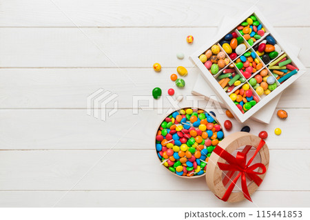 Set of different sweet candy in a paper box with a satin ribbon on a colored background. Holiday concept 115441853
