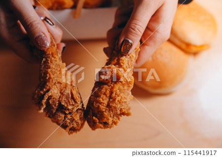 close up focus woman hand hold fried chicken for eat,girl with fast food concept close up focus woman hand hold fried chicken for eat,girl with fast food concept 115441917