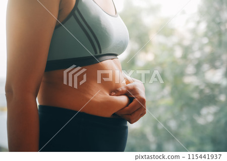 fat woman, fat belly, chubby, obese woman hand holding excessive belly fat with measure tape, woman diet lifestyle concept 115441937