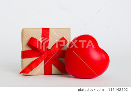 gift box with red bow and red heart on colored background. Perspective view. Flat lay gift box with red bow and red heart on colored background. Perspective view. Flat lay 115442292