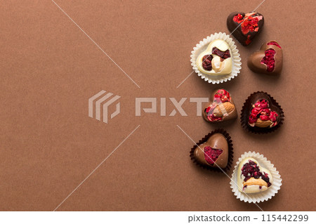chocolate sweets in the form of a heart with fruits and nuts on a colored background. top view with space for text, holiday concept 115442299