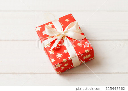 Wrapped christmas or other holiday handmade present in paper with colored ribbon. Present box, decoration of gift on table, top view with copy space 115442362