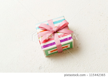 wrapped Christmas or other holiday handmade gift box in color paper with ribbon on colored background. Present box, decoration of gift on colored table, top view with copy space 115442365