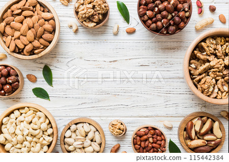 mixed nuts in wooden bowl. Mix of various nuts on colored background. pistachios, cashews, walnuts, hazelnuts, peanuts and brazil nuts 115442384