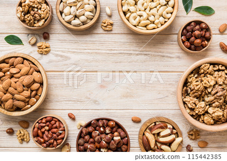 mixed nuts in wooden bowl. Mix of various nuts on colored background. pistachios, cashews, walnuts, hazelnuts, peanuts and brazil nuts mixed nuts in wooden bowl. Mix of various nuts on colored background. pistachios, cashews, walnuts, hazelnuts, peanuts and brazil nuts 115442385