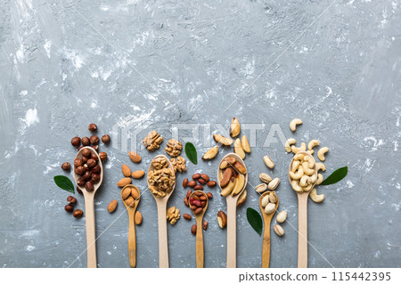 mixed nuts in white wooden spoon. Mix of various nuts on colored background. pistachios, cashews, walnuts, hazelnuts, peanuts and brazil nuts 115442395