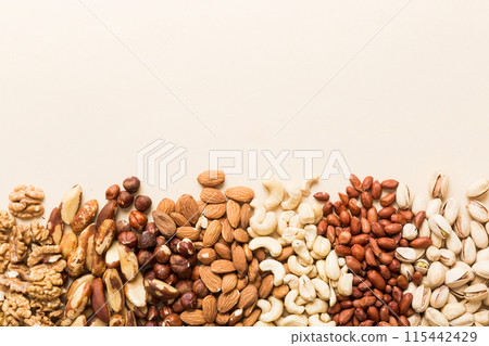 different nuts frame background. Close up, top view, flat lay with vopy space. Walnut, pistachios, almonds, hazelnuts and cashews 115442429