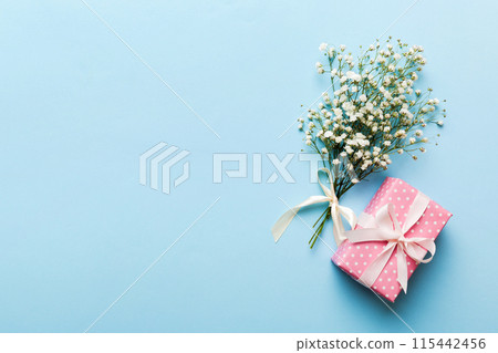 Gift or present box and flower gypsophila on light table top view. Greeting card. Flat lay style with copy space Gift or present box and flower gypsophila on light table top view. Greeting card. Flat lay style with copy space 115442456