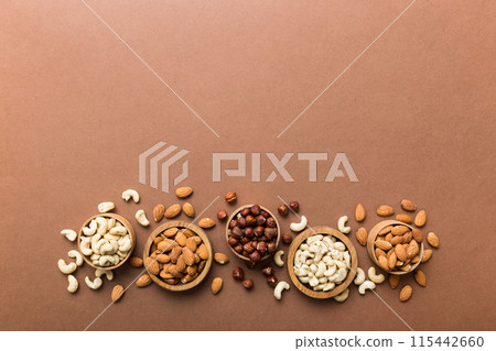 Assortment of nuts in wooden bowl on colored table. Cashew, hazelnuts, walnuts, almonds. Mix of nuts Top view with copy space 115442660