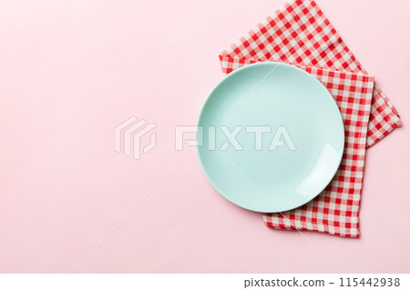 Top view on colored background empty round blue plate on tablecloth for food. Empty dish on napkin with space for your design Top view on colored background empty round blue plate on tablecloth for food. Empty dish on napkin with space for your design 115442938