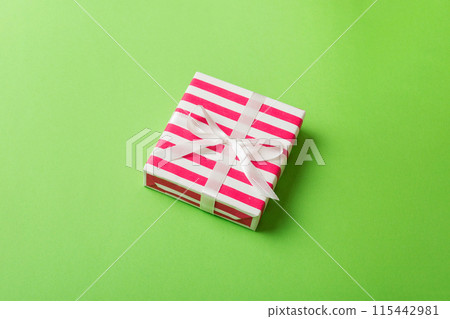 wrapped Christmas or other holiday handmade gift box in color paper with ribbon on colored background. Present box, decoration of gift on colored table, top view with copy space wrapped Christmas or other holiday handmade gift box in color paper with ribbon on colored background. Present box, decoration of gift on colored table, top view with copy space 115442981