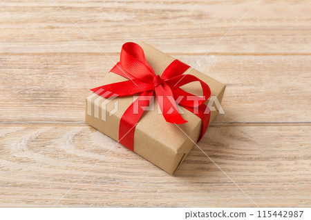 Wrapped christmas or other holiday handmade present in craft paper with colored ribbon. Present box, decoration of gift on table, top view with copy space Wrapped christmas or other holiday handmade present in craft paper with colored ribbon. Present box, decoration of gift on table, top view with copy space 115442987