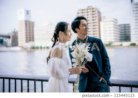 Bride and groom holding a bouquet at the beach 115443115