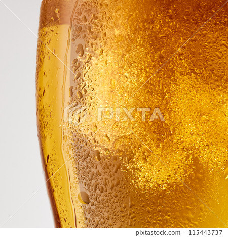 Close-up photo of cold, lager alcohol drink, beer with thick white foam against grey studio background. Close-up photo of cold, lager alcohol drink, beer with thick white foam against grey studio background. 115443737