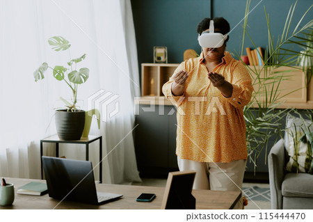Retired African American woman experiencing new technologies with help of VR headset Retired African American woman experiencing new technologies with help of VR headset 115444470