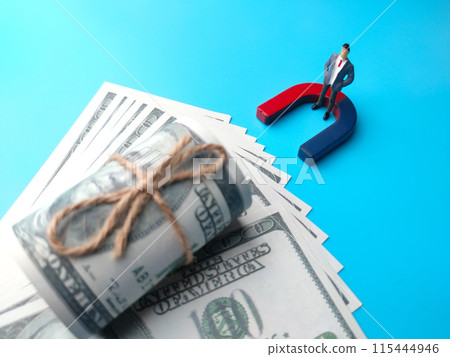 Selective focus image of miniature businessman attracts money using magnet. 115444946