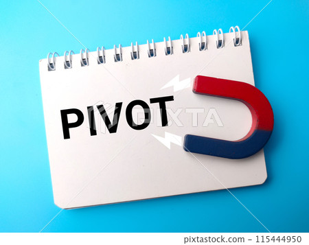 Top view notebook and attracts magnet with text PIVOT on blue background. 115444950