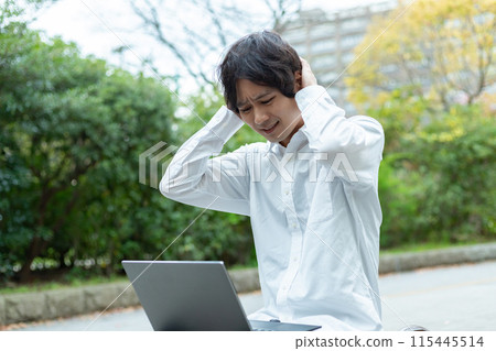 A man worried while using a laptop outdoors 115445514