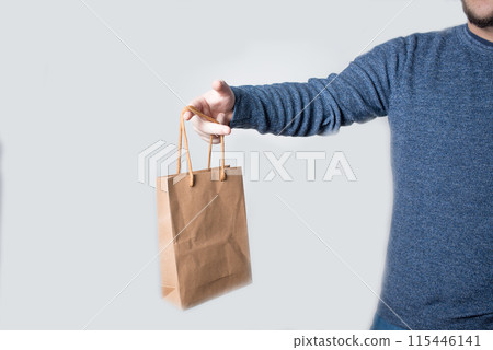 Young anonymous adult dressed with jeans and pullover delivering a brown paper bag Young anonymous adult dressed with jeans and pullover delivering a brown paper bag 115446141