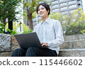 A young man operating a computer outdoors 115446602