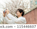 A man holding a camera at the cherry blossoms 115446607
