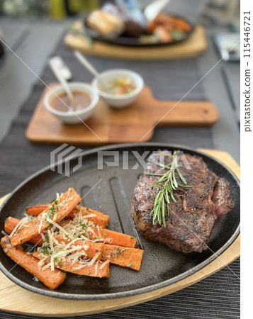 Grilled Steaks with spices rosemary and pepper on wooden board on black background. 115446721