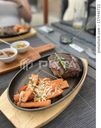 Grilled Steaks with spices rosemary and pepper on wooden board on black background. 115446722