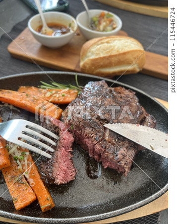 Grilled Steaks with spices rosemary and pepper on wooden board on black background. 115446724